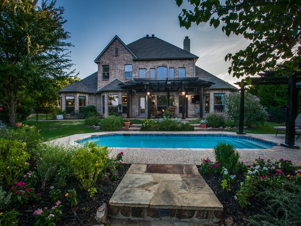 Manicured gardens under mature Oak trees leads you through the large, grassy backyard and the lake beyond. You could build a fire-pit here and watch the sun set with your friends.. 