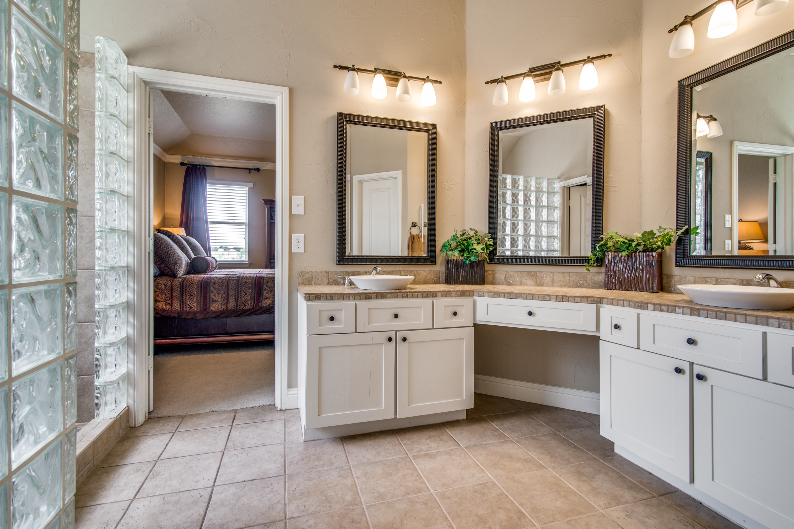 Dual sink vanities with a sitting area, walk in closet & separate standing shower.